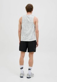 Ærmeløs, lysegrå atletisk tanktop med et tekstureret mønster, parret med sorte shorts og grå sneakers, set fra ryggen.