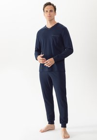 Ensemble de pyjama bleu marine en tissu doux, comprenant un haut à manches longues en v avec une poche poitrine et un pantalon fuselé assorti avec des poignets élastiques.