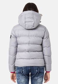 Helle graue Pufferjacke mit Kapuze, mit gestepptem Textur und elastischen Bündchen, kombiniert mit lässigen Jeans.