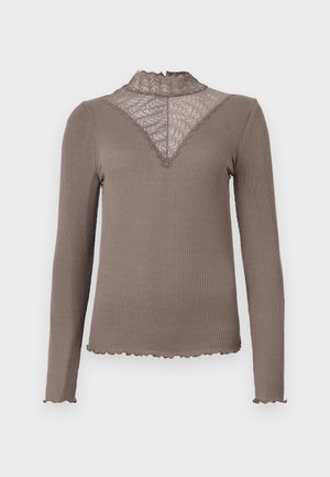 Langarmtop in taupe geribbeld materiaal met een kant yoke en gegolfde randen. Heeft een hoge rucheshals en een aansluitende pasvorm.