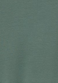 Tela en color azul verdoso con una textura fina y suave; presenta un ligero estiramiento y un patrón sutil de jaspeado. Ideal para llevar con comodidad.
