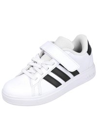 Zapatilla sintética blanca con rayas negras, diseño de cordones y una correa de Velcro cruzando la lengüeta. Suela de goma para tracción y durabilidad.