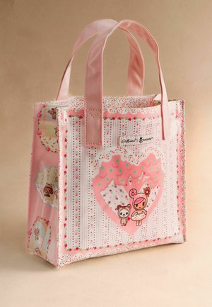 Pieni vaaleanpunainen kangaskassi, jossa on kaksi kahvaa. Kassi on koristeltu piirrettyjen hahmojen ja karkkiteemaisen kuosin avulla, ja siinä on etuosassa brändätty merkki.