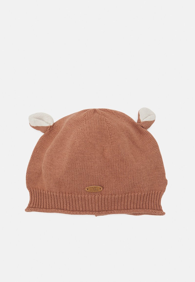Gorro de malha na cor terracota quente com uma aba canelada. Apresenta duas orelhas em bege claro na parte superior e uma pequena etiqueta de metal com o logótipo.