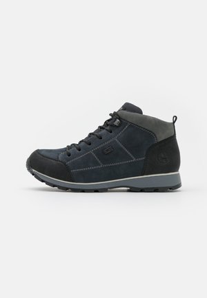 Mid-top shoes made of navy blue leather with a textured black rubber toe cap and grey accents. Features a lace-up design and sturdy sole.
