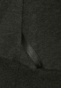 Black fabric sweater featuring a textured knit, with a leather label sewn into the side displaying brand information.