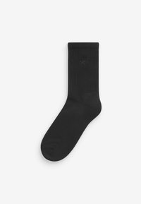 Sort bomuldsstrømpe med ribbet struktur, ankel længde, der har et subtilt præget brandnavn "self." Ingen mønstre eller hardware detaljer.