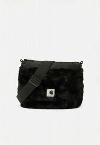 Fekete műszőrme keresztpántos táska téglalap alakú, cipzáras záródással, állítható pánttal és fehér logóbélyeggel az elején.