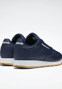 Jūros mėlynumo odiniai sportbačiai su balta terasa ir guminėmis išorinėmis dalimis. Funkcijos: "Reebok" logotipas ir tekstūruotas paviršius su siuvinėtomis detalėmis.