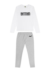 Weißes Langarmshirt mit dem Aufdruck "BATMAN" in Schwarz; kombiniert mit grauen Schlafanzughosen, die nahe dem Bund ein kleines schwarzes Fledermaus-Logo aufweisen.