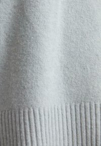 Tissu tricoté gris clair avec une texture douce et un détail de bord-côte en bas.