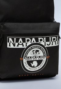 Zaino in tessuto nero con logo bianco "NAPAPIJRI", grafica circolare di ricerca antartica e dettagli arancioni. Comparto con cerniera visibile.