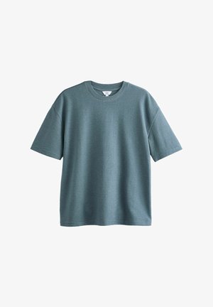 Mentza zaļa T-kreklā ar īsām piedurknēm, apaļu kakla izgriezumu, izgatavots no mīksta auduma. Tam ir nedaudz brīvs piegriezums un smalks vertikāls svītrainais raksts.