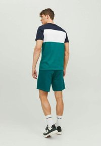 Men's athletic outfit featuring a navy, white, and teal color-blocked t-shirt and matching teal shorts, made from breathable fabric.