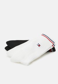 Calcetines de canalé: uno negro, uno blanco con un puño a rayas rojas y azules. Hechos de una tela suave, con un logo cerca del puño del calcetín blanco.