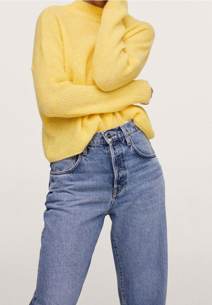 Gelber Strickpullover mit langen Ärmeln, kombiniert mit hellblauen High-Waist-Jeans. Der Pullover hat eine lockere Passform und eine weiche Textur.
