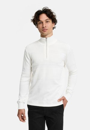 Hvid zip-up pullover med høj krave, der har strukturerede mønstersektioner og glatte områder. Fremstillet af blødt stof med en tætsiddende design.