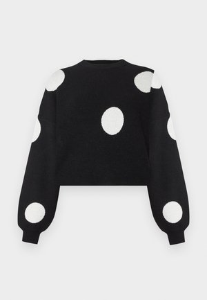 Black cropped sweater with long sleeves, featuring large white polka dots on the body and sleeves. Made from a soft, textured fabric.
