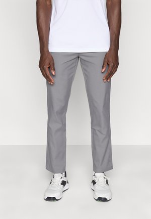 Grå bukser lavet af glat stof med et lige bukseben. Brugt sammen med hvide sportssko, der fremhæver et rent, minimalistisk design.