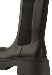 Svart läderankelboot med elastisk panel, robust plattformssula och elegant design. Ytan verkar slät med detaljerad sömnad.