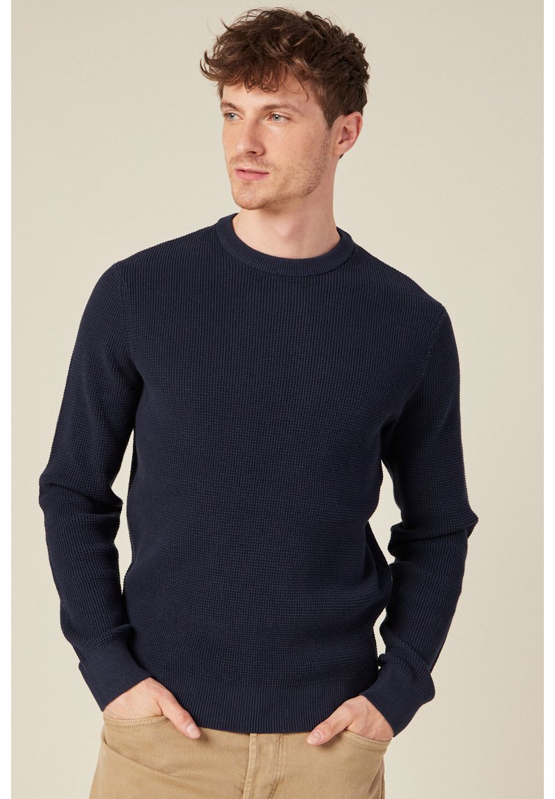 Maglione strutturato blu navy con design a maglia a costine, scollatura a girocollo e maniche lunghe. Leggero elastico con polsini e orlo aderenti.