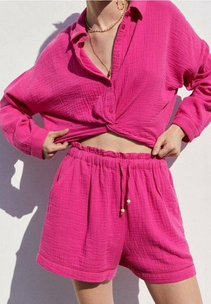 Lyserød, cropped skjorte med knapper foran og knyttet kant, kombineret med matchende shorts med elastisk linning og lommer.