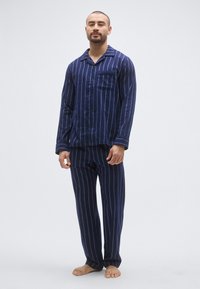Granatowy pasiasty komplet piżamy z długim rękawem i spodnie, z koszulą na guziki i kieszenią na piersi, wykonany z miękkiego materiału.
