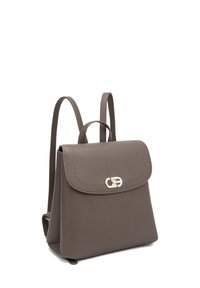 Zaino in pelle taupe compatto con fibbia dorata e spallacci regolabili, in posizione verticale su sfondo bianco.