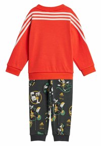 Felpa rossa con tre strisce bianche sulle spalle; pantaloni neri con stampe colorate di personaggi Disney e accenti verdi.