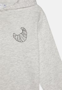 Kapuzensweatshirt aus einem hellgrauen Baumwollmix mit einer schwarzen Umrandung eines aufgestickten Croissants auf der Brust. Weiche Textur, lässiges Design.