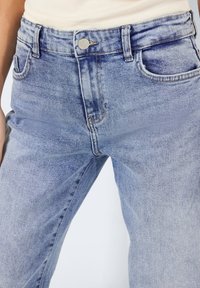 Ljusblå denimjeans med en blekt tvätt, fem fickor och en standard framknäppning, med en rak bendesign.