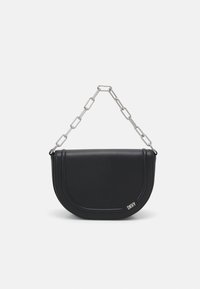 Sac à main semi-circulaire noir avec anse en chaîne argentée et petit logo DKNY argenté dans le coin inférieur droit sur un fond blanc.
