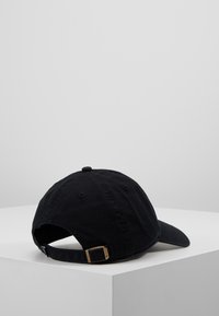 Black cotton baseball cap with curved brim, adjustable strap, and metallic buckle at the back. Features stitched eyelets for breathability.