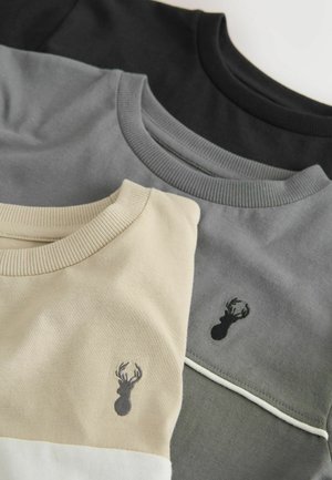 Trys apvalia kakleline megztiniai juodos, pilkos ir smėlinės spalvų; turi siaurus rievėtus kaklo apykaklius ir omarelio motyvą ant smėlinio megztinio priekinės dalies.