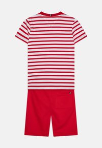 Rød og hvidstribet kortærmet T-shirt med V-hals, parret med røde shorts med en baglomme og lille trikoteret detalje.
