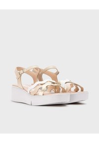 Sandalias de plataforma beige y blancas con diseño recortado, correas texturizadas y hebilla ajustable en el tobillo. Suela de espuma para mayor comodidad y soporte.