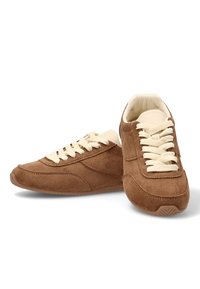 Zapatillas de ante marrón con cordones crema, punta redondeada, superficie texturizada y diseño minimalista. Forro interior suave para mayor comodidad.