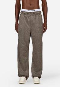 Svetlohnedé, textúrované široké nohavice s elastickým pásom, na ktorom je biele značenie "PEGADOR". Navrhnuté pre pohodlie a uvoľnený strih.
