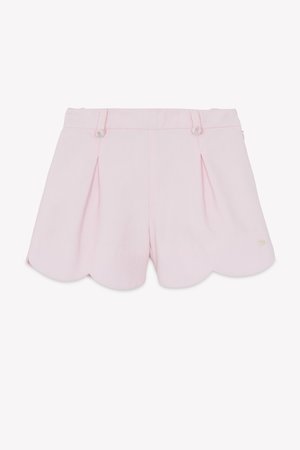 Világos rózsaszín nadrág rövidnadrág pliszírozott részletekkel, hullámos szegéllyel, két előlapos gombbal, virágmintás díszítéssel és texturált anyagból. Zsebek nem láthatók.