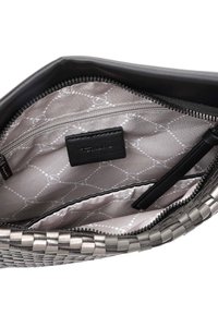 Vue intérieure d'un sac à main noir tissé montrant une poche zippée et une doublure en tissu de marque avec un motif géométrique et une étiquette en cuir.