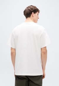 Λευκό βαμβακερό μπλουζάκι με κοντά μανίκια, στρογγυλή λαιμόκοψη και άνετη εφαρμογή. Λεία υφή, μίνιμαλ σχεδιασμός, χωρίς ορατά μοτίβα ή διακοσμητικά στοιχεία.