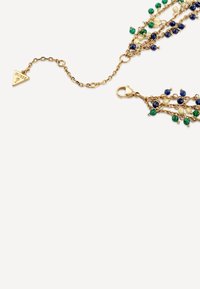 Gouden ketting met watervalletjes van kettingen, versierd met blauwe, groene en parelmoer kralen. Inclusief een sluiting en een driehoekig label met merkdetails.