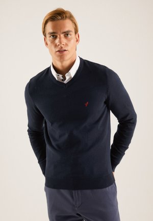 Navy V-neck sweater made of fabric with a smooth texture; features a small red logo on the chest and ribbed cuffs and hem.