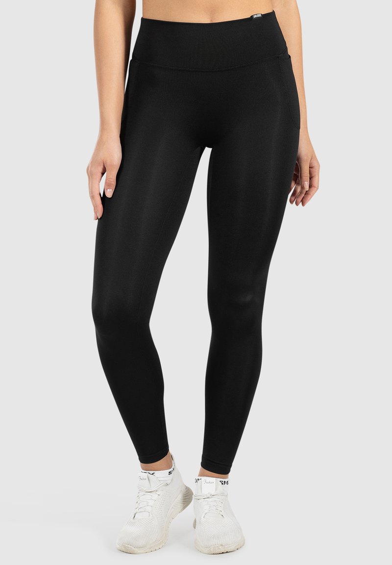 Zwarte legging gemaakt van rekbaar, glad materiaal. Hoogtaille ontwerp met een nauwsluitende pasvorm en zonder zichtbare patronen of hardware.