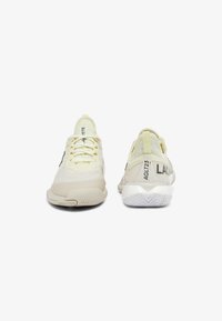 Sneaker bianche e gialle chiare in tessuto a rete, suola in gomma, logo nero a contrasto e linguetta posteriore; punta arrotondata e chiusura con lacci.