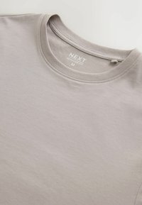 Světle šedé bavlněné tričko s kulatým výstřihem, na vnitřní straně límce je potisk s nápisem "NEXT Regular Fit M".