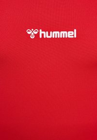 Rotes Sportshirt aus glattem Stoff mit einem weißen "hummel"-Logo in der Mitte. Einfaches Design mit Rundhalsausschnitt.