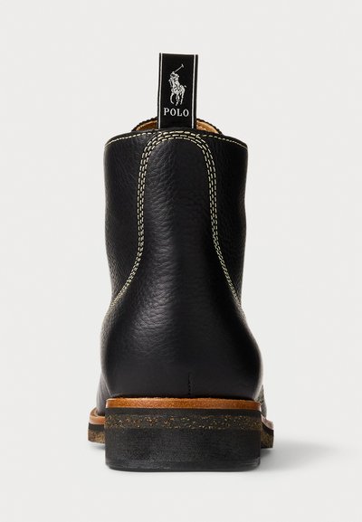 Stivaletto nere in pelle con finitura texturizzata, cuciture chiare a contrasto e suola in gomma marrone. Presenta un'etichetta con il marchio sul retro.