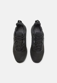 Schwarze Sportschuhe mit einem strukturierten Mesh-Obermaterial, verstärkter Zehenkappe, gepolstertem Zungenbereich und kontrastierenden Schnürsenkeln. Glatte Gummisohle für guten Halt.