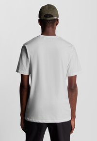 Witte katoenen t-shirt met een ronde hals en korte mouwen, gezien vanuit de achterkant. Eenvoudig ontwerp zonder patronen of accenten.